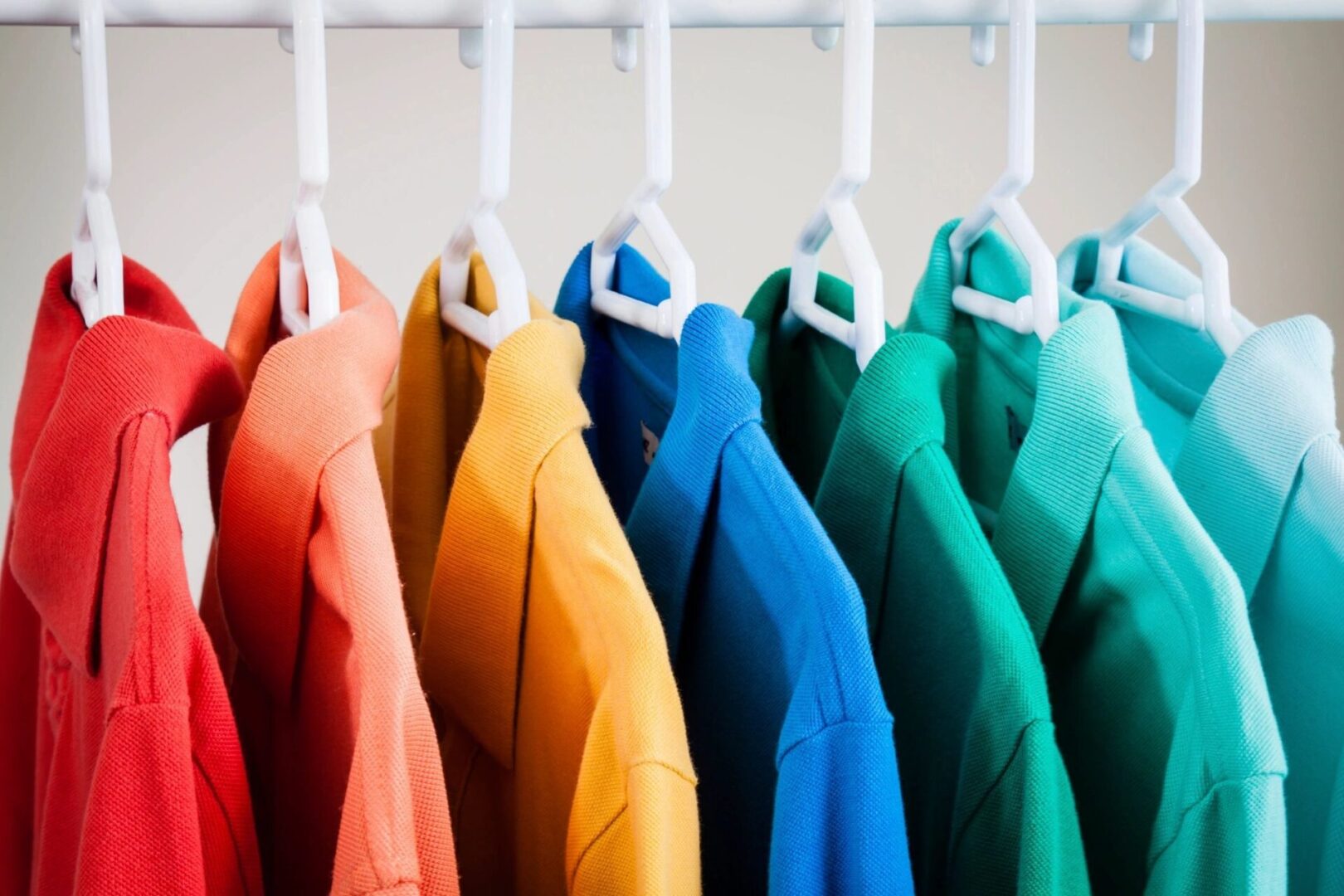 A row of jackets hanging on white hangers.