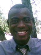 A man smiling for the camera in front of trees.