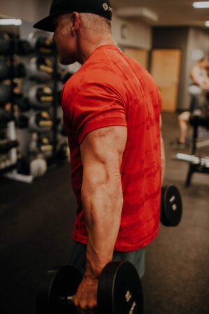 A man in red shirt holding a weight.