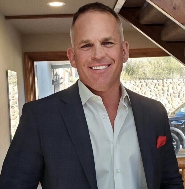 A man in a suit and tie smiling for the camera.