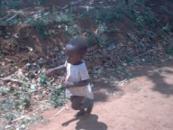 A young boy is walking on the dirt.