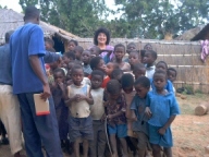 A group of children and adults in front of a fence.