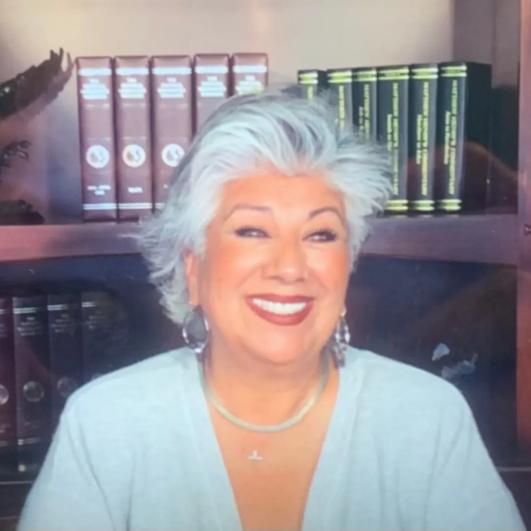 A woman with white hair sitting in front of some books.